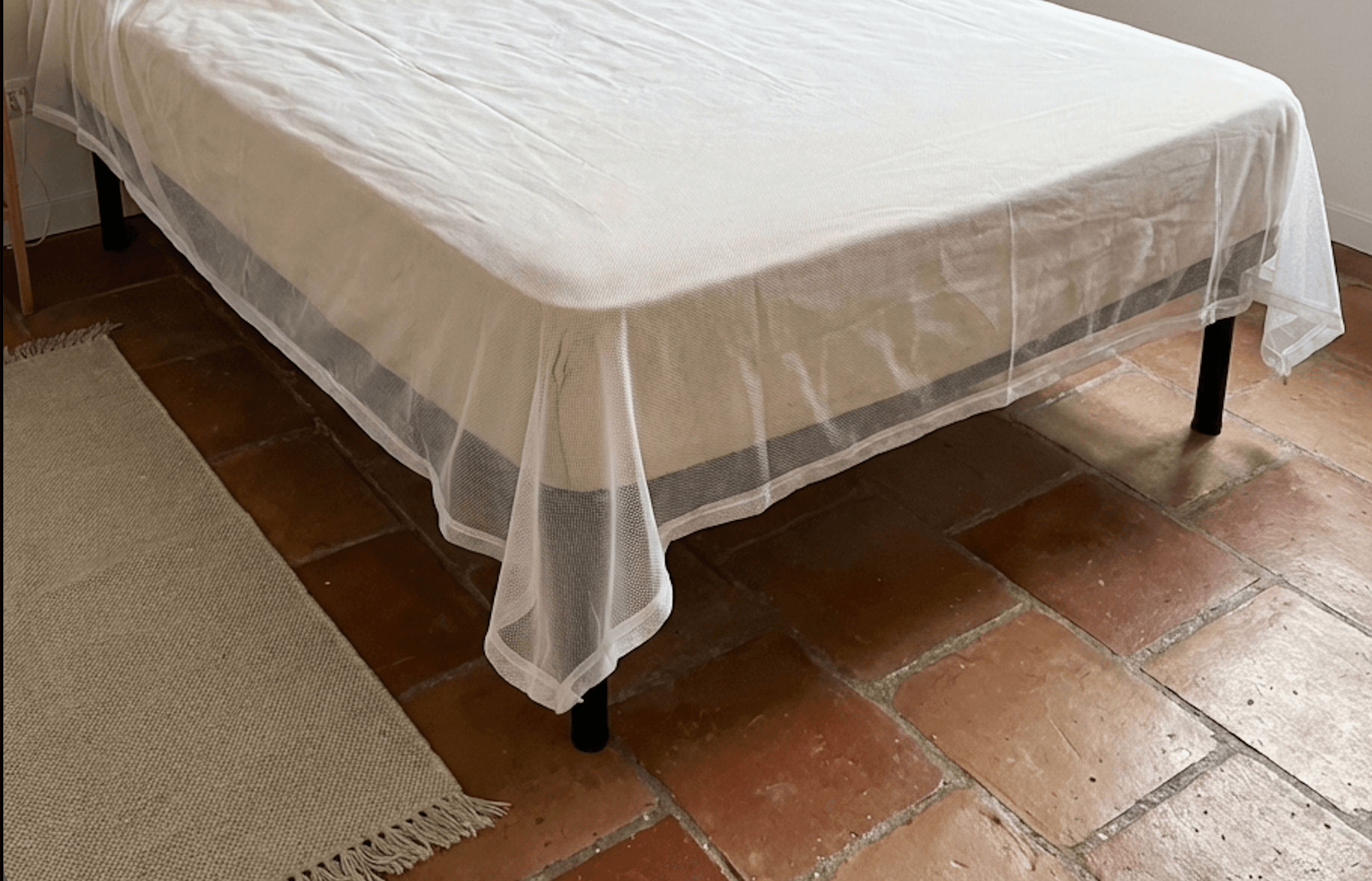 Mosticare Materasso WHO-prequalified envelope mattress mosquito net shown mid-installation on a European single mattress.